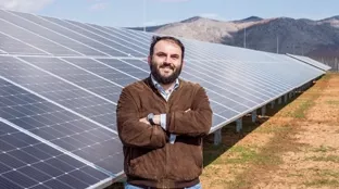 Customer in front of solar panels in Greece